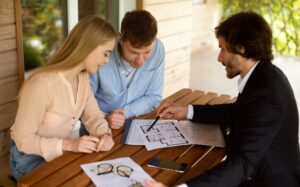 property-manager-showing-house-plan-to-his-clients-at-table-on-porch